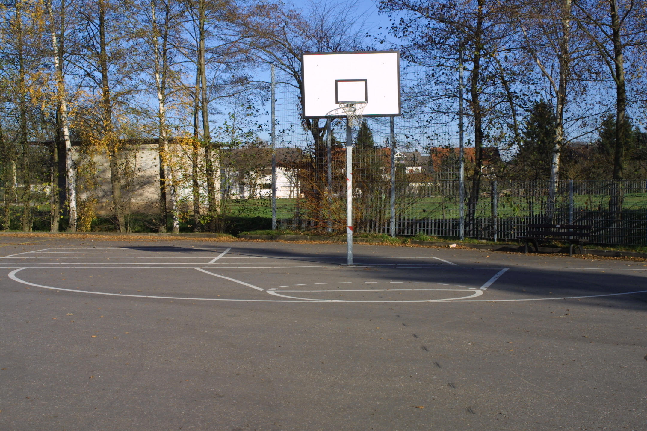 Geteerter Platz mit Basketballkorb und Feldmarkierungen