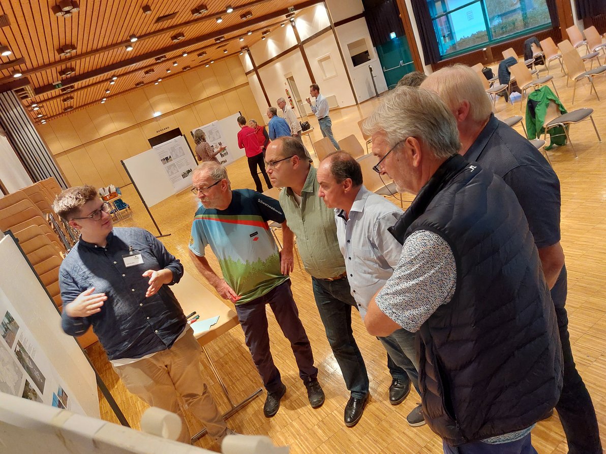 Teilnehmer:innen diskutieren vor einer Stellwand bei der Bürgerwerkstatt zum Radverkehrskonzept