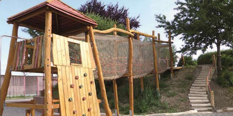 Der Kletterturm auf dem Spielplatz des Mehrgenerationenparks mit einer Brücke, um die ein Netz gespannt ist